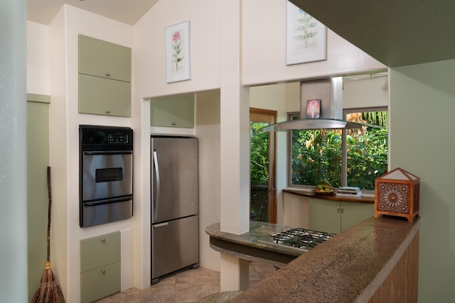 kitchen with island exhaust hood, green cabinets, dark stone countertops, and stainless steel appliances