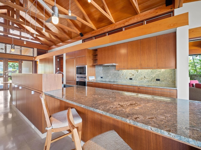 3100 Wailea Alanui Dr Unit 12, Kihei, HI 96753 - kitchen with oven, built in microwave, brown cabinetry, wooden ceiling with exposed beams, and backsplash