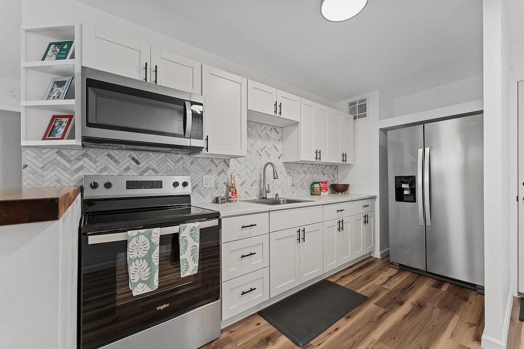 kitchen featuring dark hardwood / wood-style floors, white cabinetry, sink, and appliances with stainless steel finishes