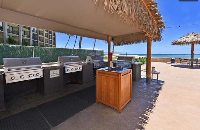 view of patio with a water view, a grill, and exterior kitchen