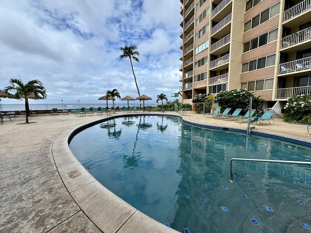 view of swimming pool featuring a patio and a water view