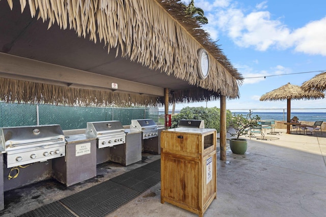 view of patio / terrace with a water view, an outdoor kitchen, and grilling area