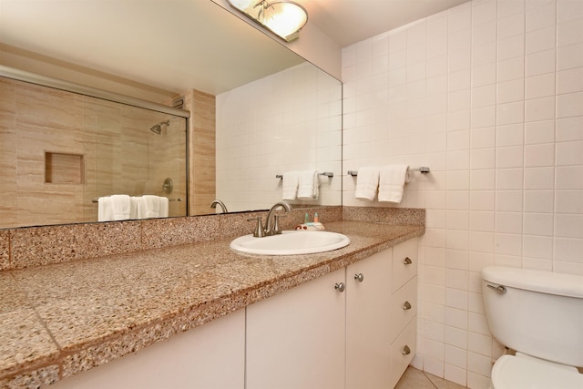 bathroom featuring toilet, large vanity, and tile walls