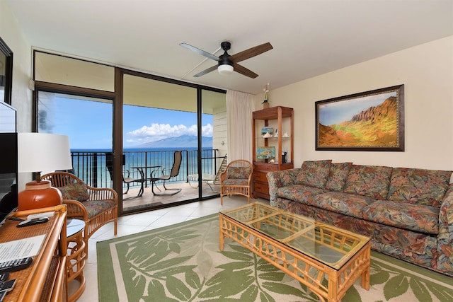 living room featuring a wall of windows, ceiling fan, light tile floors, and a water view