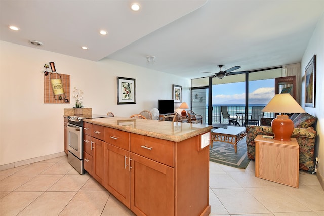 kitchen featuring light stone counters, light tile floors, stainless steel electric range, a wall of windows, and ceiling fan