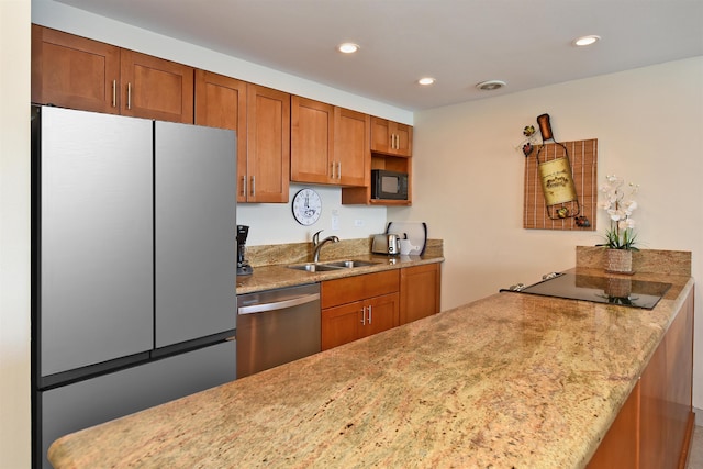 kitchen with kitchen peninsula, light stone counters, sink, and stainless steel appliances