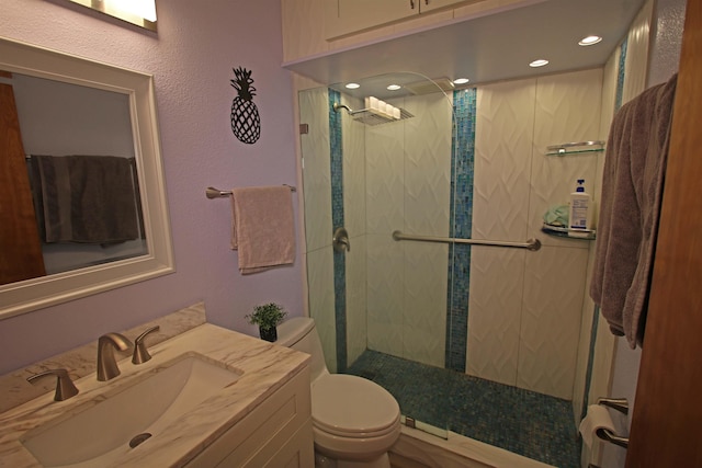 bathroom with toilet, tiled shower, and vanity