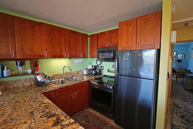 kitchen with light stone countertops, sink, a textured ceiling, and stainless steel appliances