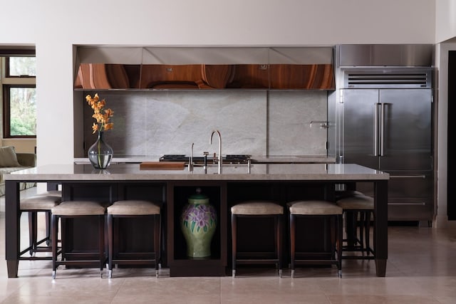 kitchen featuring sink, tasteful backsplash, a breakfast bar, and high end fridge