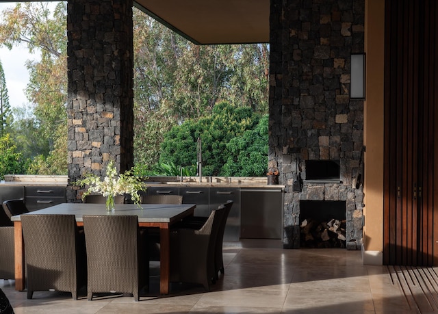 tiled dining room featuring sink and an outdoor stone fireplace