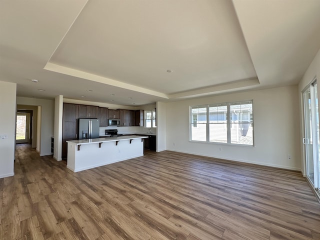 kitchen with a kitchen bar, a kitchen island, stainless steel appliances, and hardwood / wood-style flooring