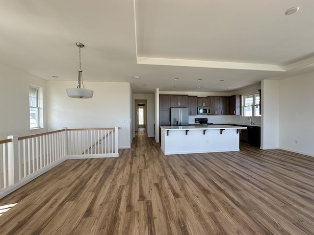 kitchen with hardwood / wood-style floors, a kitchen breakfast bar, hanging light fixtures, dark brown cabinetry, and stainless steel appliances
