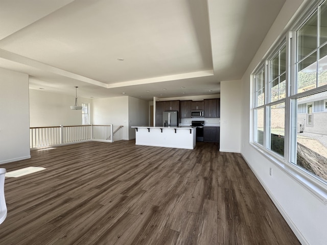 unfurnished living room featuring dark hardwood / wood-style floors and a tray ceiling