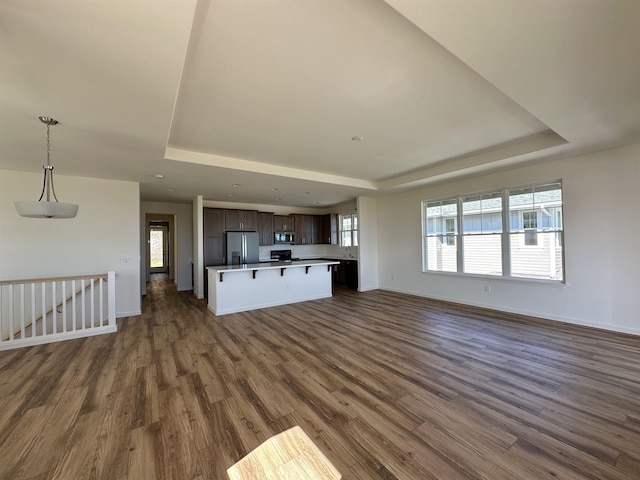 unfurnished living room with a tray ceiling and dark hardwood / wood-style floors