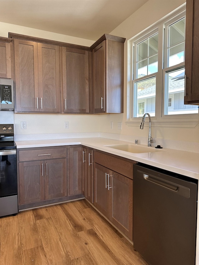 kitchen with stainless steel appliances, light hardwood / wood-style floors, and sink