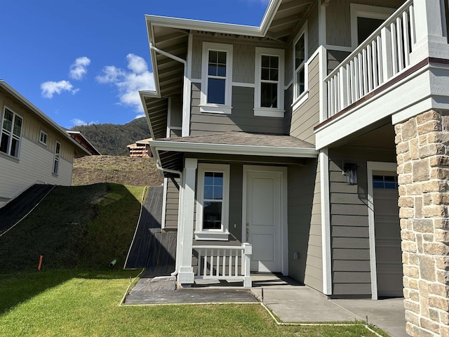 view of exterior entry featuring a lawn and a balcony