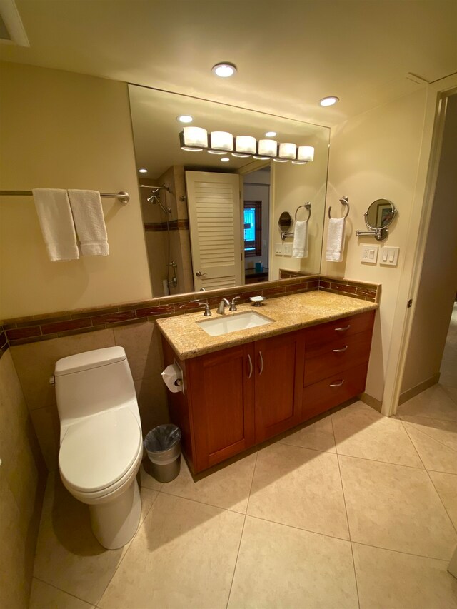 bathroom with vanity, toilet, tile floors, and tile walls