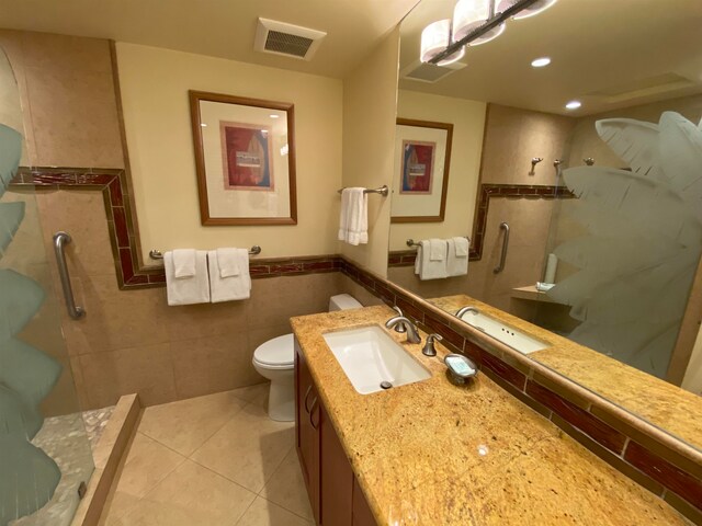 bathroom with a tile shower, oversized vanity, toilet, and tile walls