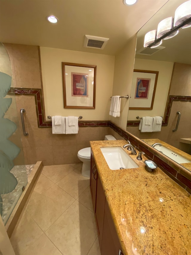 bathroom featuring tile flooring, tile walls, a shower, vanity with extensive cabinet space, and toilet