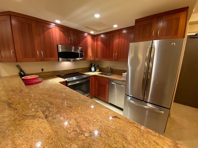 kitchen featuring appliances with stainless steel finishes, sink, light stone countertops, and light tile flooring