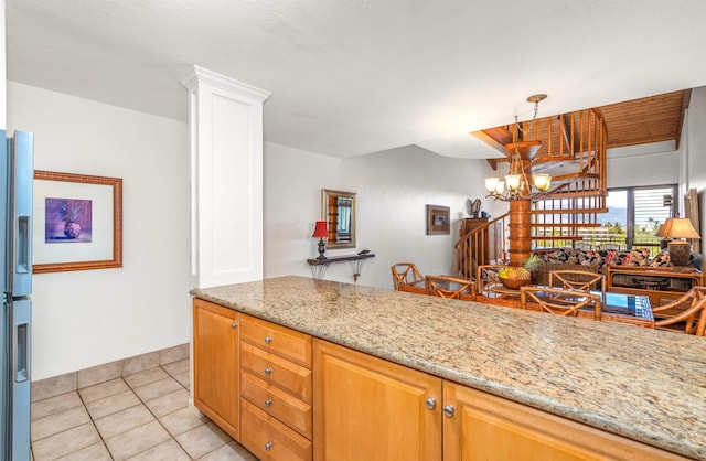kitchen featuring light stone countertops, stainless steel refrigerator with ice dispenser, a notable chandelier, and light tile patterned floors