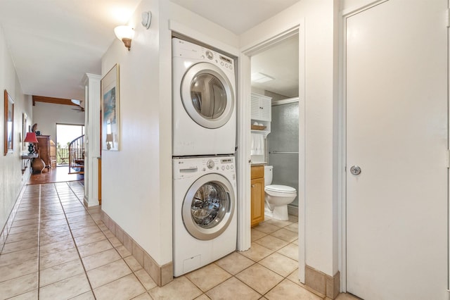laundry room featuring stacked washer / drying machine, laundry area, and light tile patterned flooring