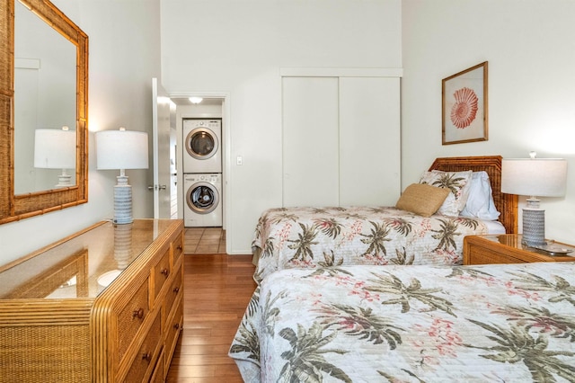 bedroom with stacked washer and dryer, wood finished floors, and a closet