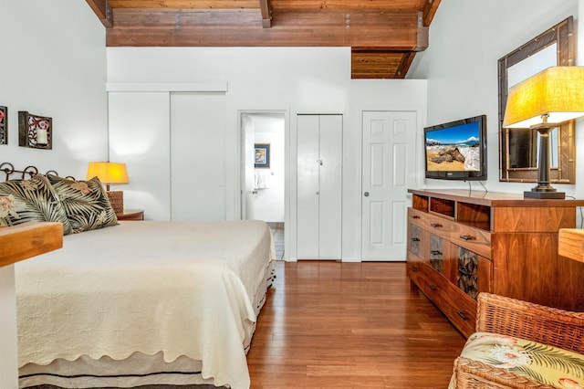bedroom with beamed ceiling, wood finished floors, multiple closets, and wood ceiling