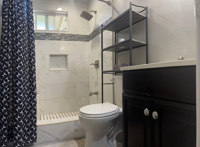 bathroom with a tile shower and toilet