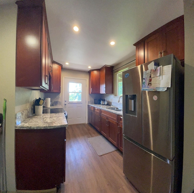 kitchen with light stone countertops, stainless steel fridge, light hardwood / wood-style floors, and sink