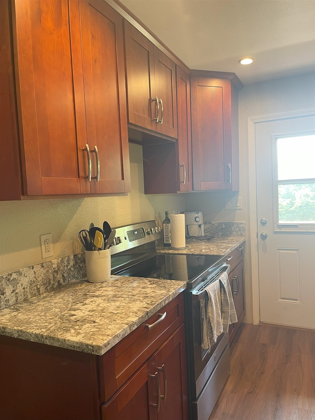 kitchen featuring light stone counters, dark wood-type flooring, and electric stove