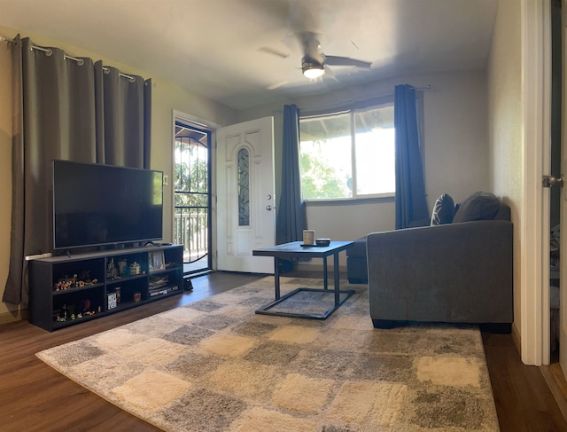 living room featuring ceiling fan and dark wood-type flooring