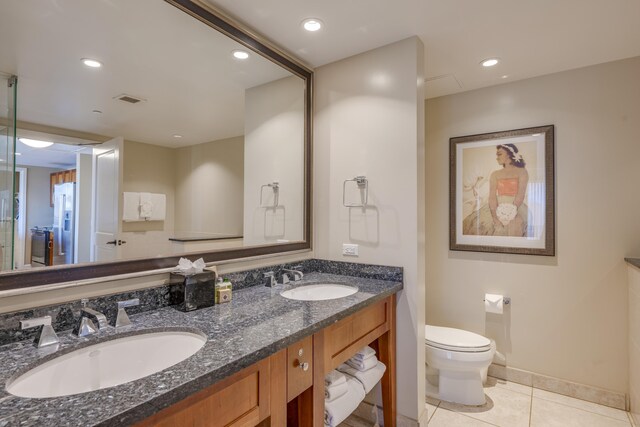 bathroom with toilet, vanity, and tile patterned flooring