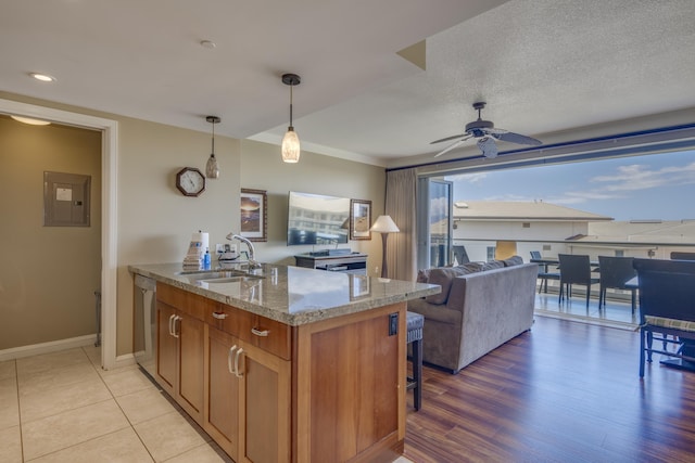 kitchen featuring decorative light fixtures, ceiling fan, sink, light stone counters, and electric panel