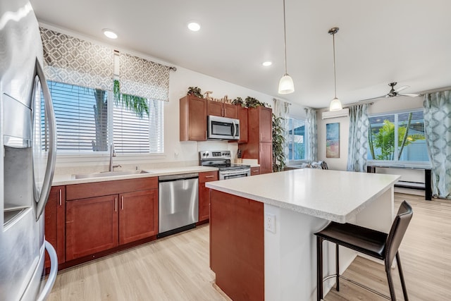 kitchen featuring a kitchen island, a breakfast bar, pendant lighting, sink, and stainless steel appliances