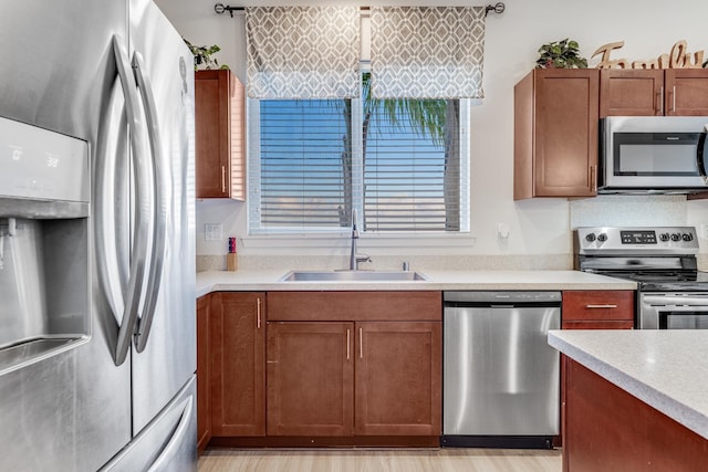 kitchen with stainless steel appliances, sink, and light wood-type flooring