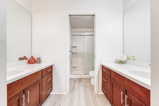 bathroom featuring hardwood / wood-style flooring, vanity, an enclosed shower, and toilet