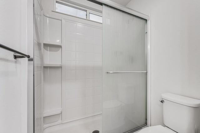 bathroom featuring toilet and a shower with shower door