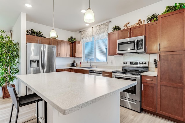 kitchen with a kitchen island, sink, a breakfast bar area, hanging light fixtures, and stainless steel appliances