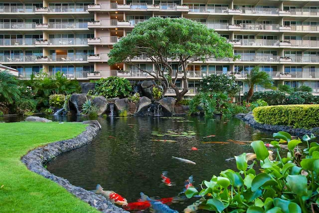 view of home's community with a small pond and a yard