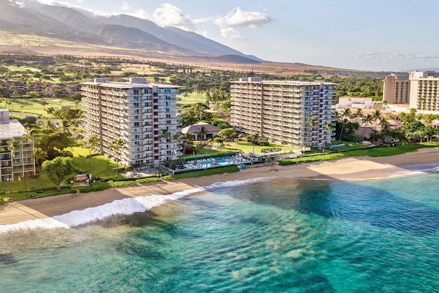 drone / aerial view featuring a water and mountain view and a beach view