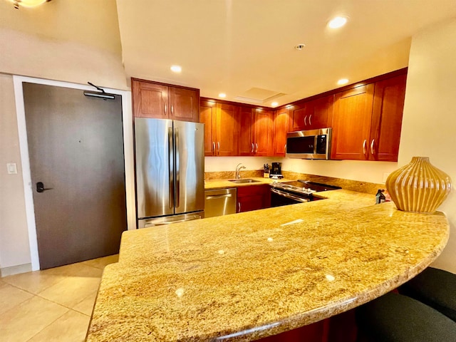 kitchen featuring kitchen peninsula, sink, light stone countertops, light tile patterned floors, and appliances with stainless steel finishes