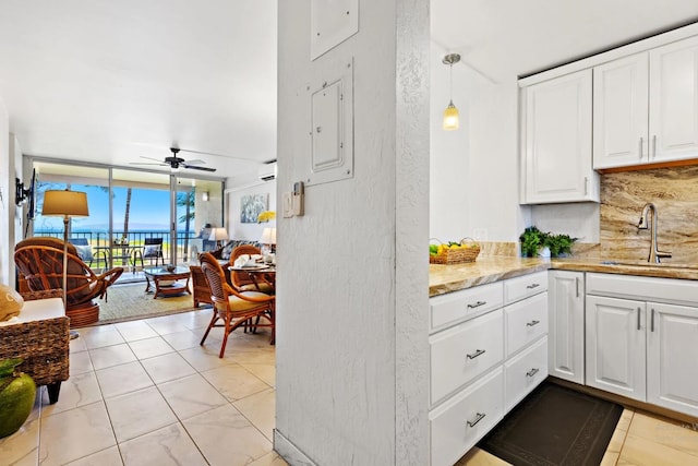 kitchen featuring backsplash, sink, hanging light fixtures, ceiling fan, and white cabinetry