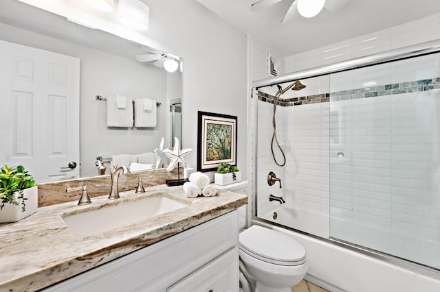 full bathroom featuring ceiling fan, vanity, bath / shower combo with glass door, and toilet