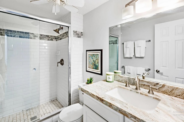 bathroom featuring vanity, toilet, a shower with door, and ceiling fan