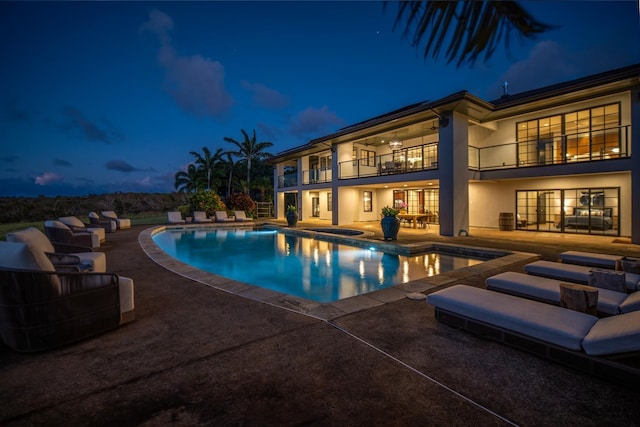 pool at dusk with a patio area and a hot tub