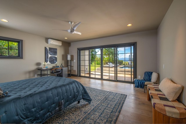 bedroom with a wall mounted air conditioner, access to exterior, hardwood / wood-style flooring, and ceiling fan