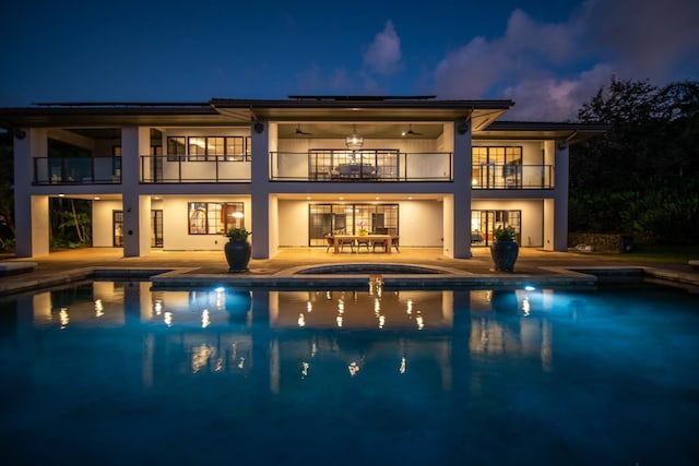 rear view of property with solar panels, a balcony, and a patio area