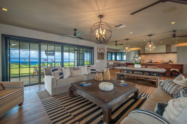 living room with ceiling fan with notable chandelier and hardwood / wood-style flooring