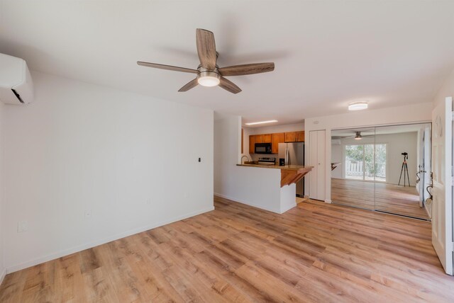 160 Keonekai Rd Unit 9-102, Kihei, HI 96753 - unfurnished living room with a wall mounted AC, ceiling fan, and light hardwood / wood-style flooring